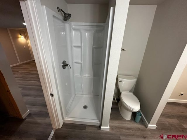 bathroom with a shower, hardwood / wood-style floors, and toilet