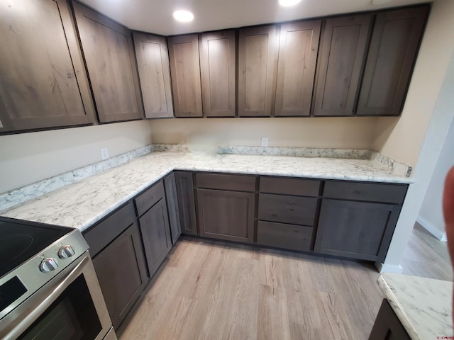 kitchen with light stone countertops, light wood-type flooring, electric stove, and dark brown cabinetry