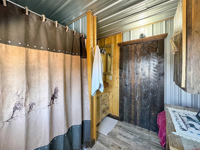 bathroom with wood walls and hardwood / wood-style flooring