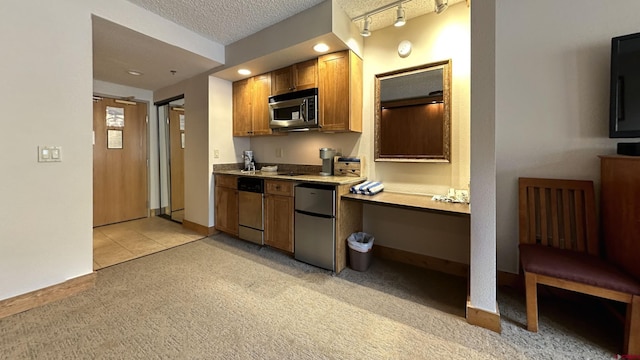 kitchen featuring light colored carpet, a textured ceiling, appliances with stainless steel finishes, and track lighting