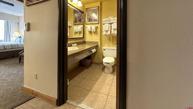 bathroom featuring toilet, tile patterned flooring, sink, and a textured ceiling