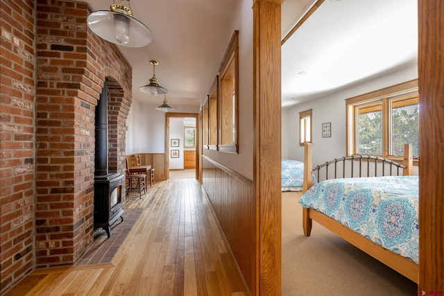 bedroom with a wood stove and light wood-type flooring