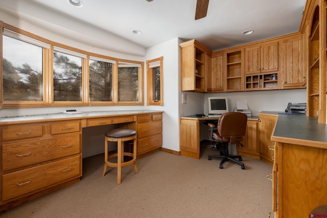 carpeted office space with ceiling fan and built in desk