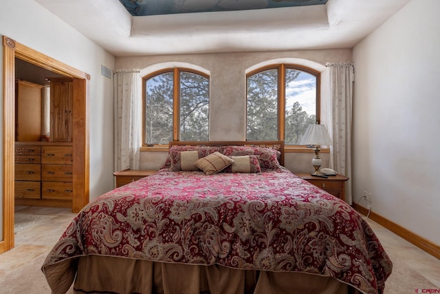 tiled bedroom with a tray ceiling and multiple windows