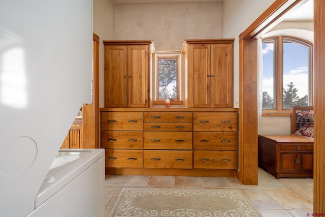 bathroom with independent washer and dryer, tile floors, and a wealth of natural light