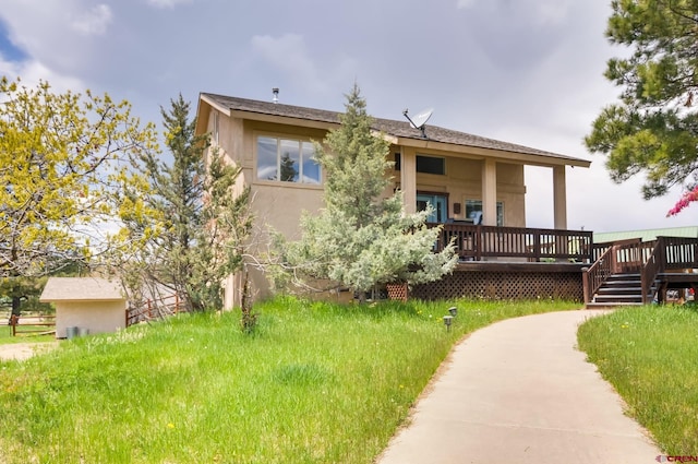 back of property featuring a deck and a lawn