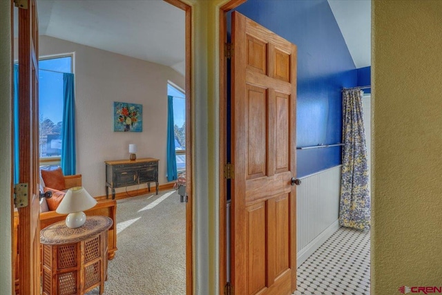 corridor featuring light colored carpet and vaulted ceiling