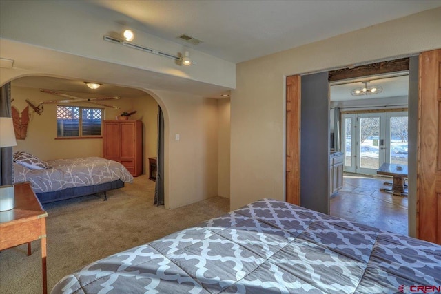 carpeted bedroom with a notable chandelier, french doors, and multiple windows