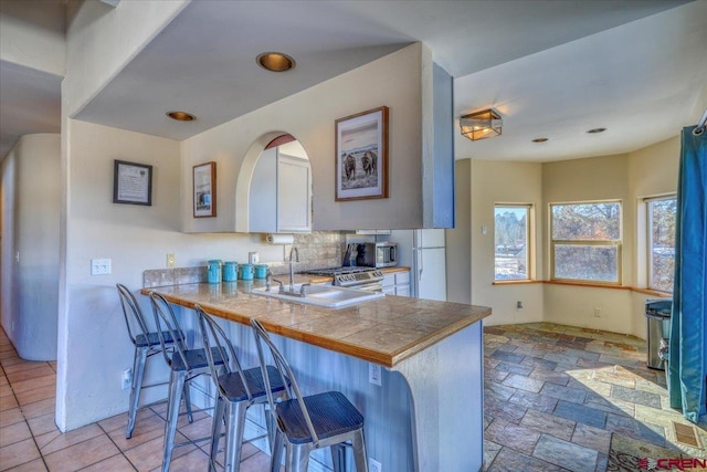 kitchen with white cabinets, a kitchen bar, light tile floors, and kitchen peninsula