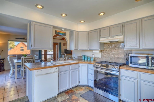 kitchen featuring stainless steel appliances, kitchen peninsula, premium range hood, and dark tile floors