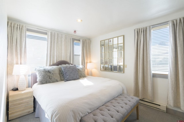 bedroom with multiple windows, a baseboard heating unit, and carpet flooring