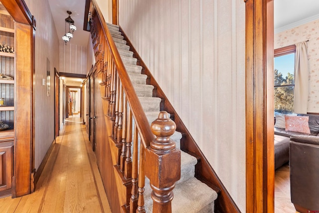 stairs featuring a barn door, light hardwood / wood-style floors, and crown molding