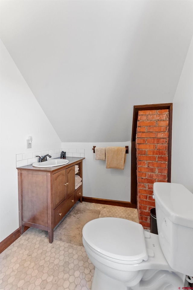 bathroom featuring lofted ceiling, tile flooring, toilet, and vanity