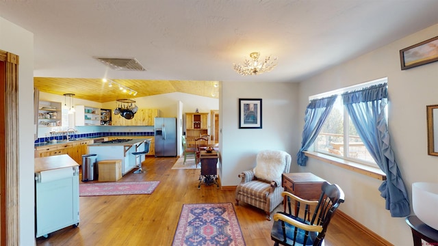 kitchen featuring sink, black gas cooktop, an inviting chandelier, stainless steel refrigerator with ice dispenser, and hardwood / wood-style flooring