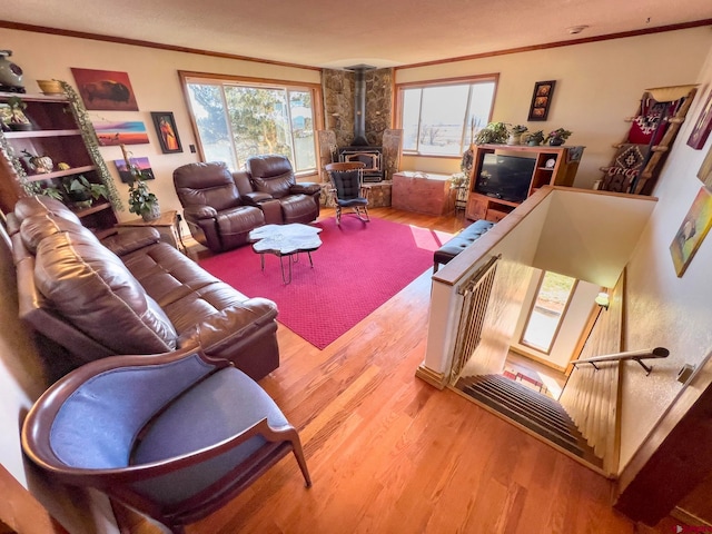 living room featuring crown molding, a wood stove, and light wood-type flooring