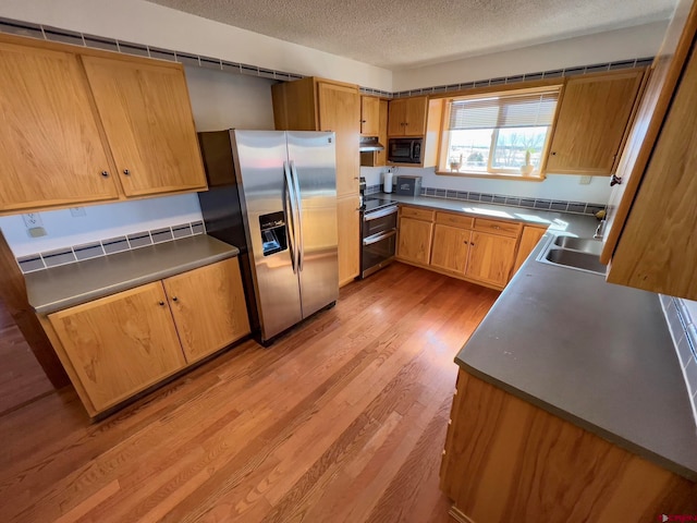 kitchen featuring light hardwood / wood-style floors, stainless steel appliances, a textured ceiling, and sink