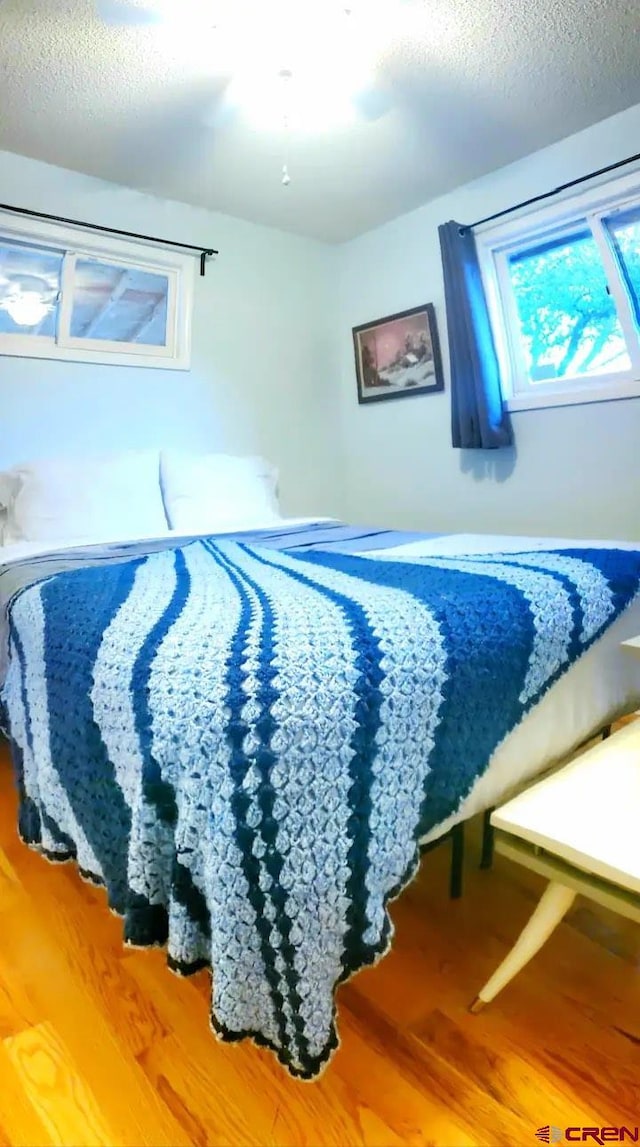 bedroom with a textured ceiling and wood-type flooring