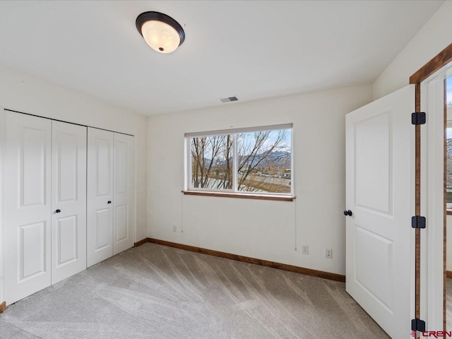 unfurnished bedroom with a closet and light colored carpet