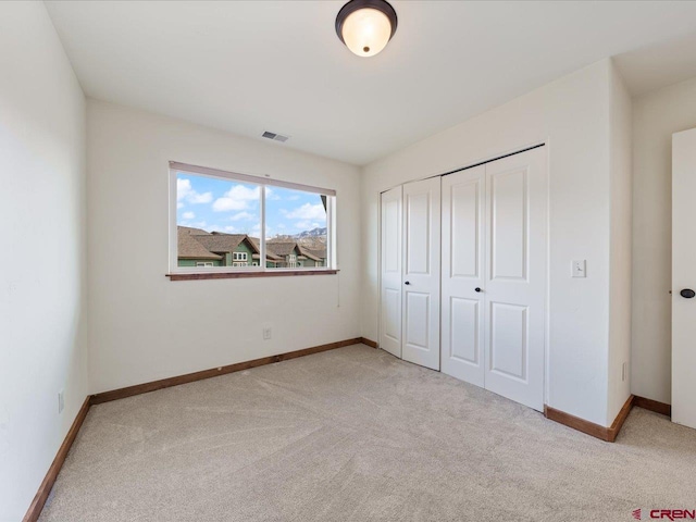 unfurnished bedroom featuring light carpet and a closet