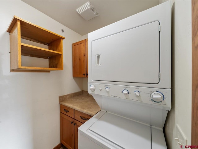 washroom featuring cabinets and stacked washer / dryer