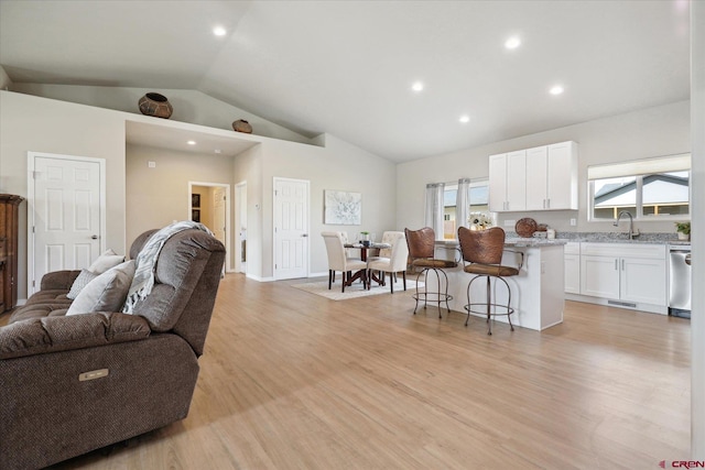 living room with sink, vaulted ceiling, and light wood-type flooring