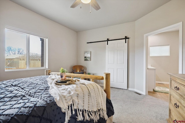 carpeted bedroom featuring a barn door, multiple windows, and ceiling fan