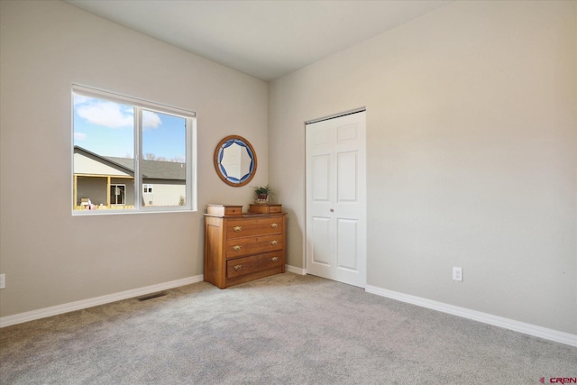 unfurnished bedroom with light carpet and a closet