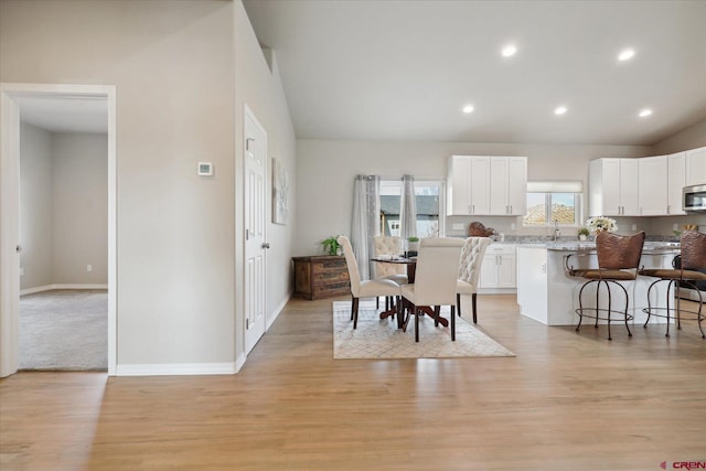 dining space with light hardwood / wood-style floors and vaulted ceiling