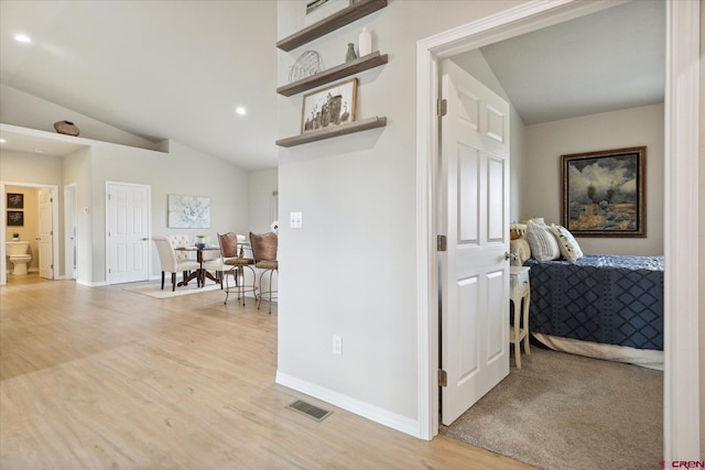 corridor featuring light colored carpet and vaulted ceiling