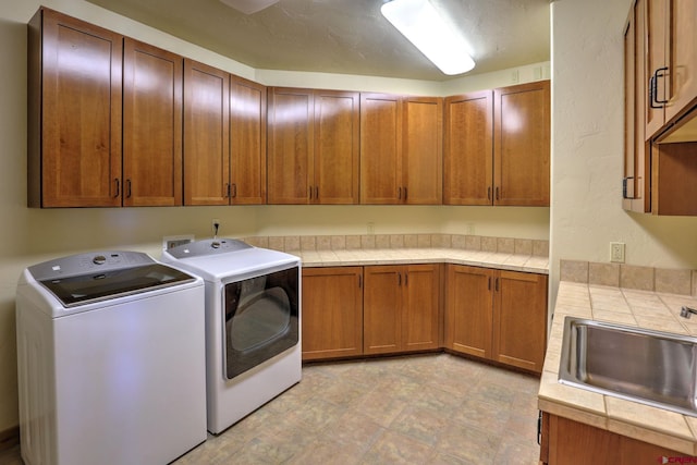 clothes washing area featuring sink, cabinets, independent washer and dryer, and light tile floors