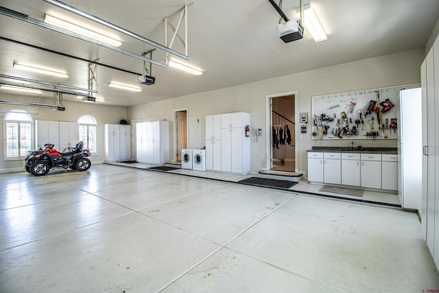 garage with a garage door opener, a workshop area, and independent washer and dryer