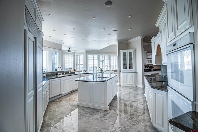 kitchen with kitchen peninsula, ceiling fan, light tile floors, sink, and double oven