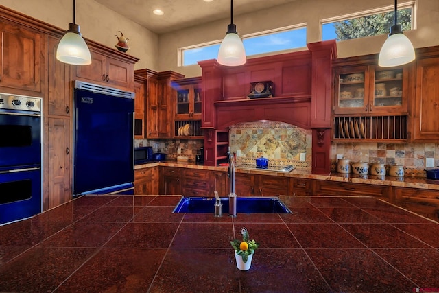 kitchen with pendant lighting, tasteful backsplash, a towering ceiling, sink, and black appliances