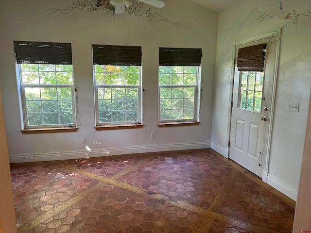 tiled empty room with ceiling fan and a wealth of natural light