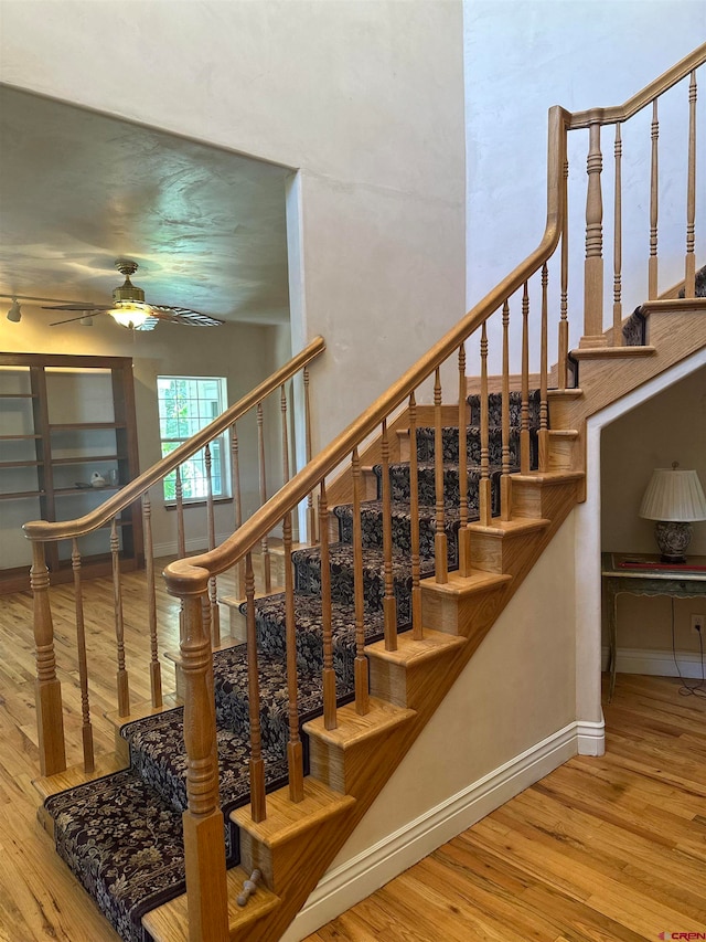 stairs with ceiling fan and light hardwood / wood-style flooring