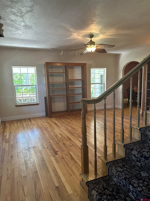 staircase featuring light hardwood / wood-style floors and ceiling fan