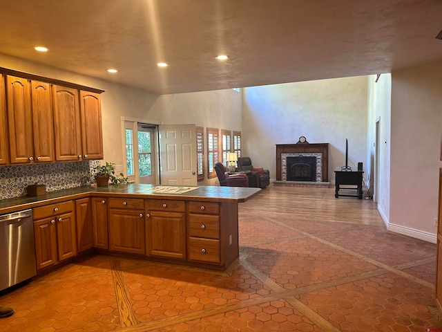 kitchen featuring a brick fireplace, stainless steel dishwasher, light tile floors, and tasteful backsplash