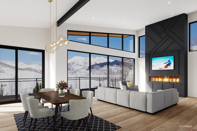 dining space with beam ceiling, light wood-type flooring, a chandelier, and a mountain view