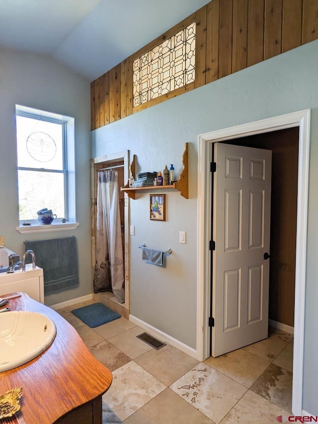 bathroom with tile flooring, vaulted ceiling, and sink