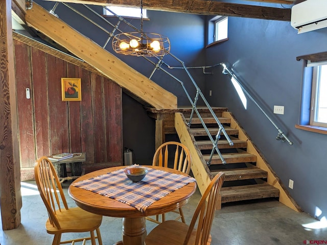 dining area with a chandelier, a healthy amount of sunlight, wood walls, and a wall unit AC