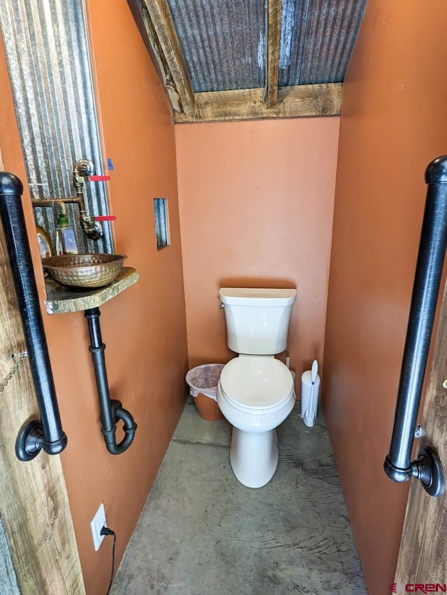 bathroom with concrete flooring and toilet