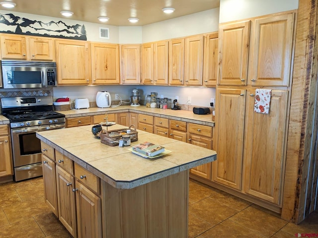 kitchen featuring dark tile floors, stainless steel appliances, and a center island