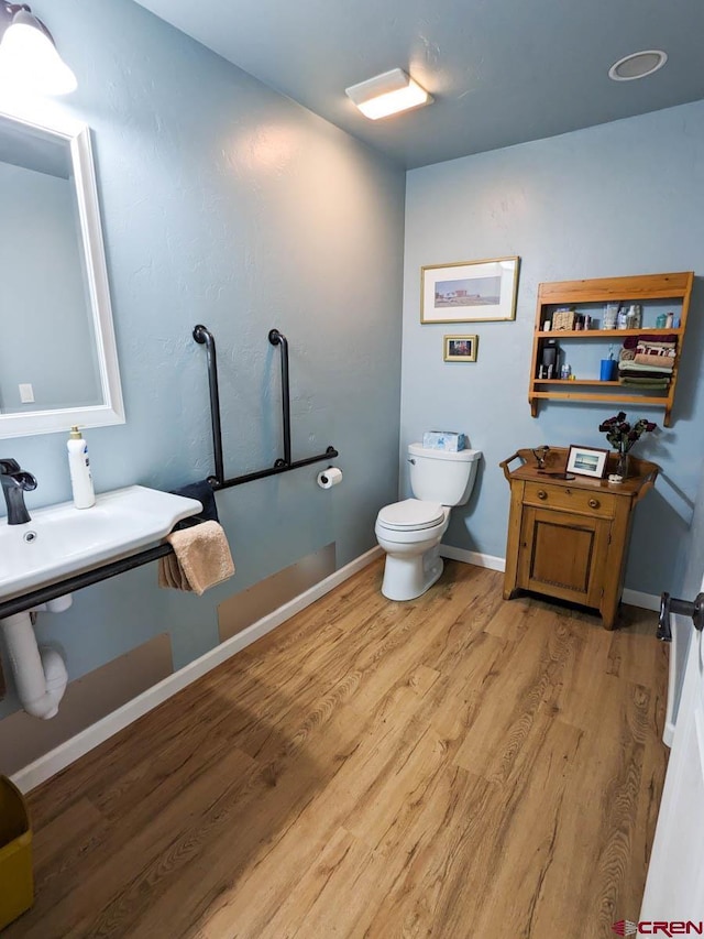 bathroom with toilet and hardwood / wood-style flooring