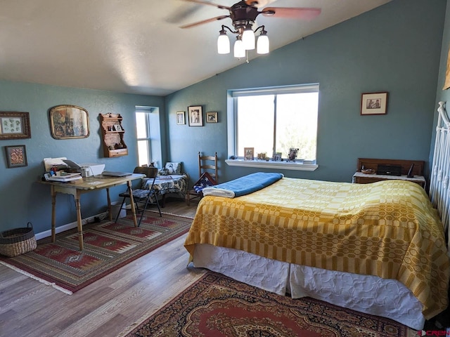 bedroom with ceiling fan, dark wood-type flooring, and vaulted ceiling