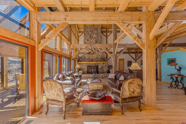 living room featuring a stone fireplace, light wood-type flooring, and beam ceiling