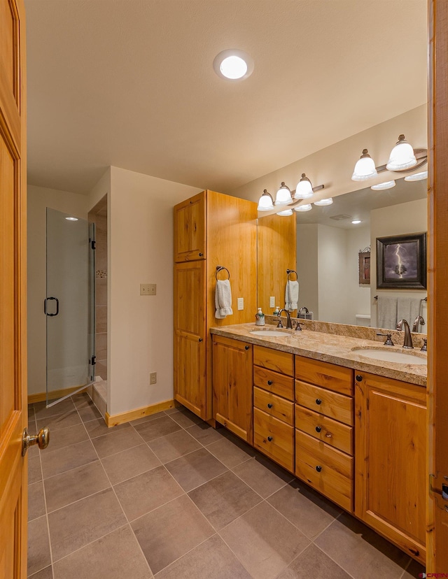 bathroom featuring a shower with door, dual vanity, and tile floors