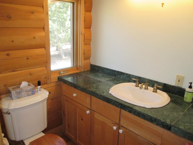 bathroom featuring toilet, wood walls, vanity, and a wealth of natural light