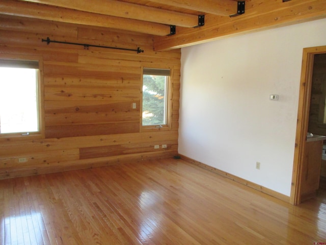 empty room with beam ceiling and light hardwood / wood-style floors