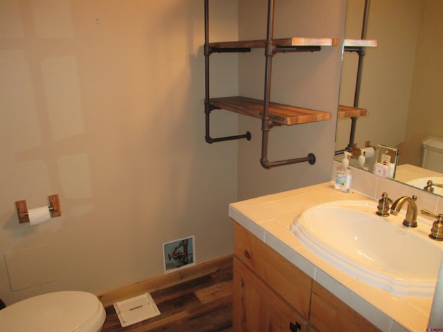 bathroom with toilet, vanity, and hardwood / wood-style flooring