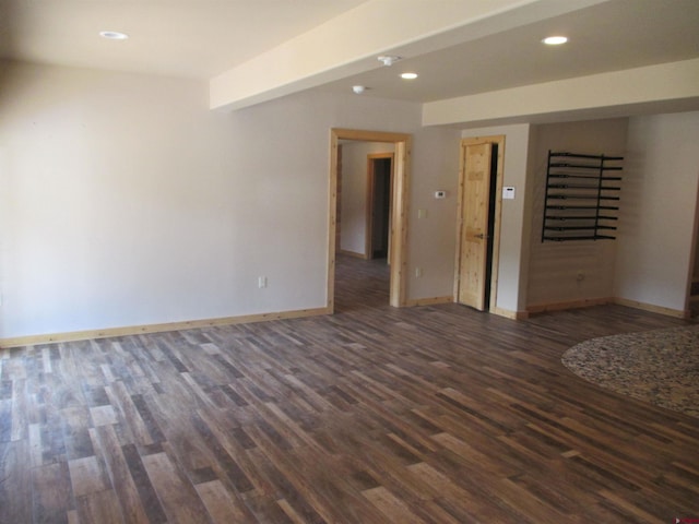 spare room with dark hardwood / wood-style flooring and beamed ceiling